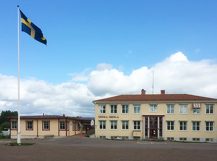 Gul skolbyggnad och flaggstång.