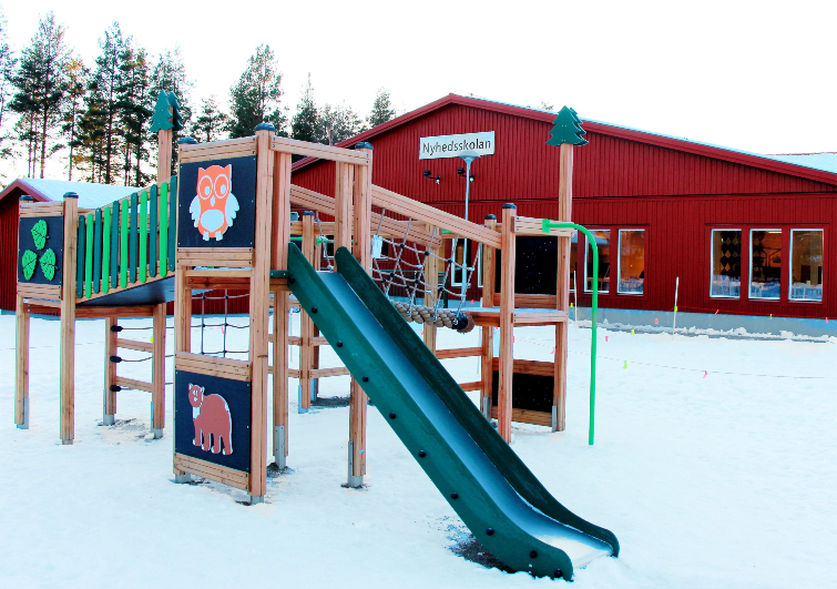 Nyhedsskolan med lekparken på skolgården i förgrunden.