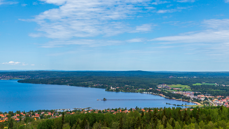 Utsikt från Vidablick över Siljan och Långbryggan. På marken syns hus och grön skog.