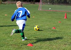 Pojke som tränar fotboll på en gräsplan