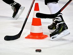 Hockeyskridskor, koner och hockeyklubbar på isen.