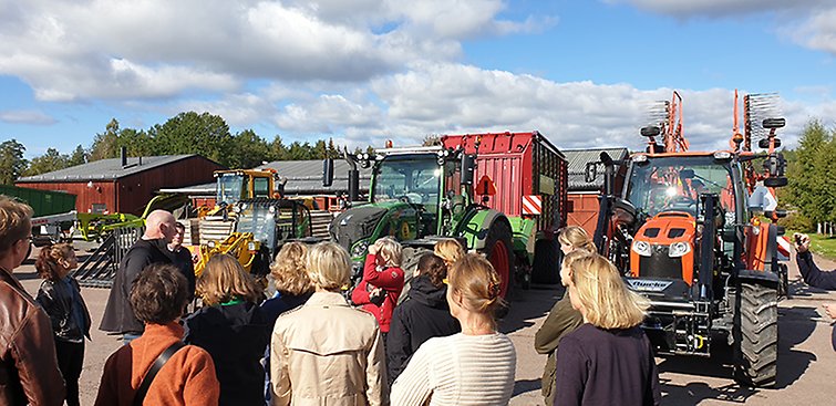 Många människor tittar på skolans traktorer vid maskinhallen.