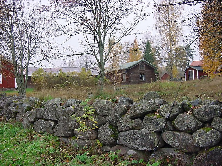 Stengärdsgård med äldre byggnader och höstfärger i bakgrunden.