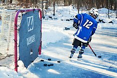 En kille i blå hockeytröja som åker skridskor framför ett hockeymål