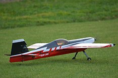Rött och vitt modellflygplan start klart på gräset.