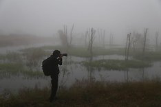 Fotograf ute i naturen vid en sjö med dimma.
